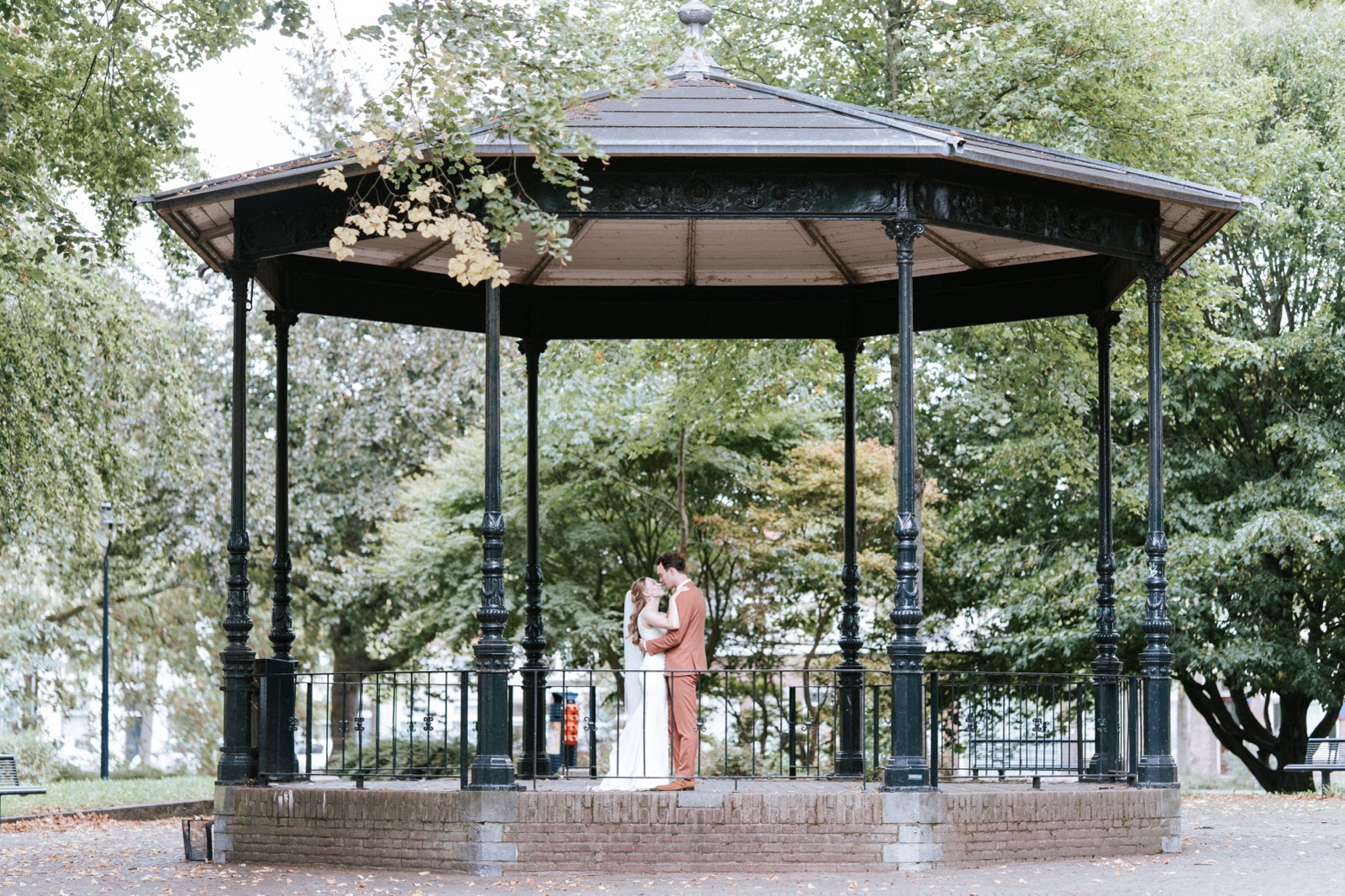 Bruidspaar in een sierlijke muziektent in het park