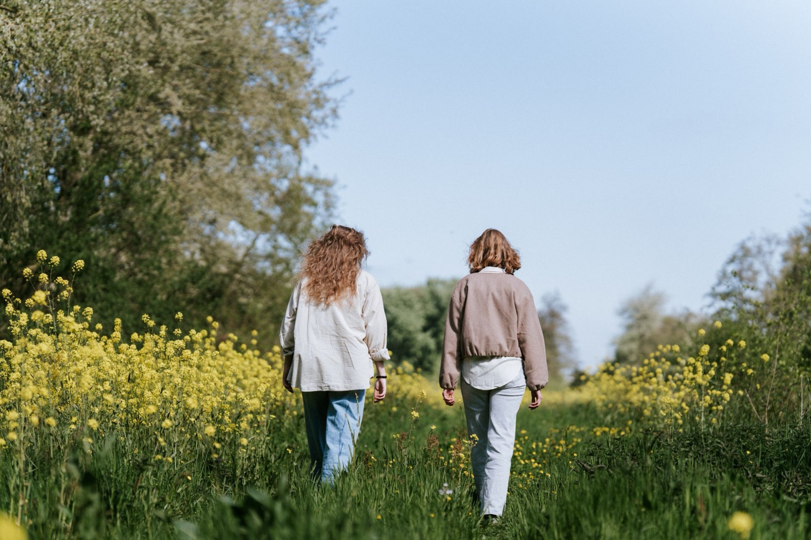 Ellen en een deelnemer lopen samen over een pad tussen bloeiend koolzaad