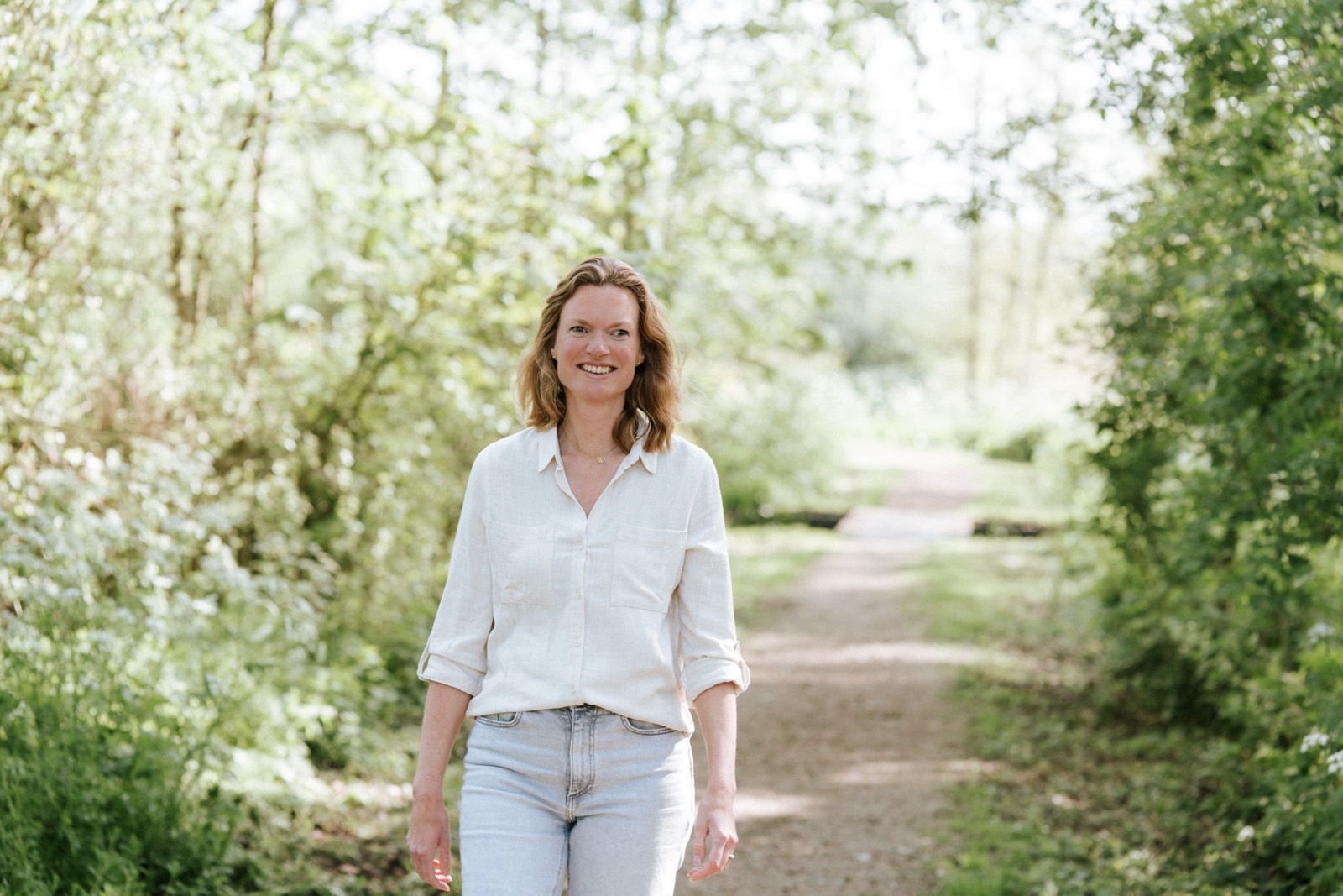 Wandelcoach Ellen loopt over een groen bospad