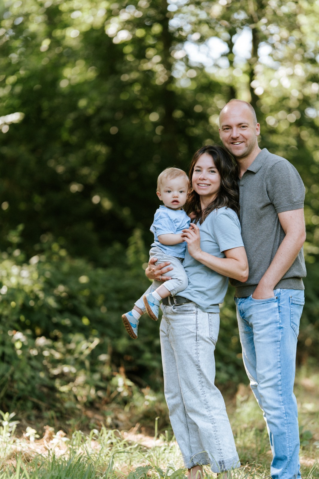 Ouders met hun peuter tussen het groen in het bos