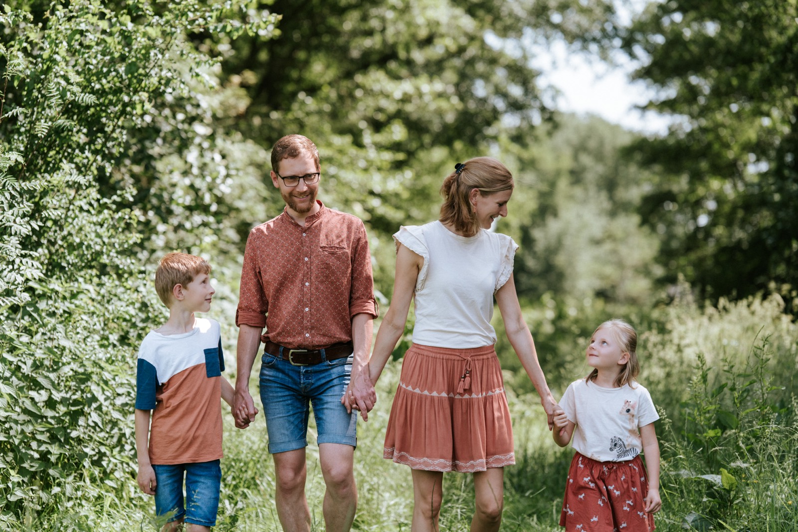 Gezin met twee kinderen hand in hand op een bospad