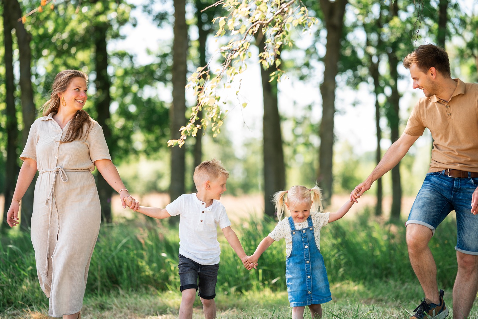 Gezin rent lachend hand in hand door het bos