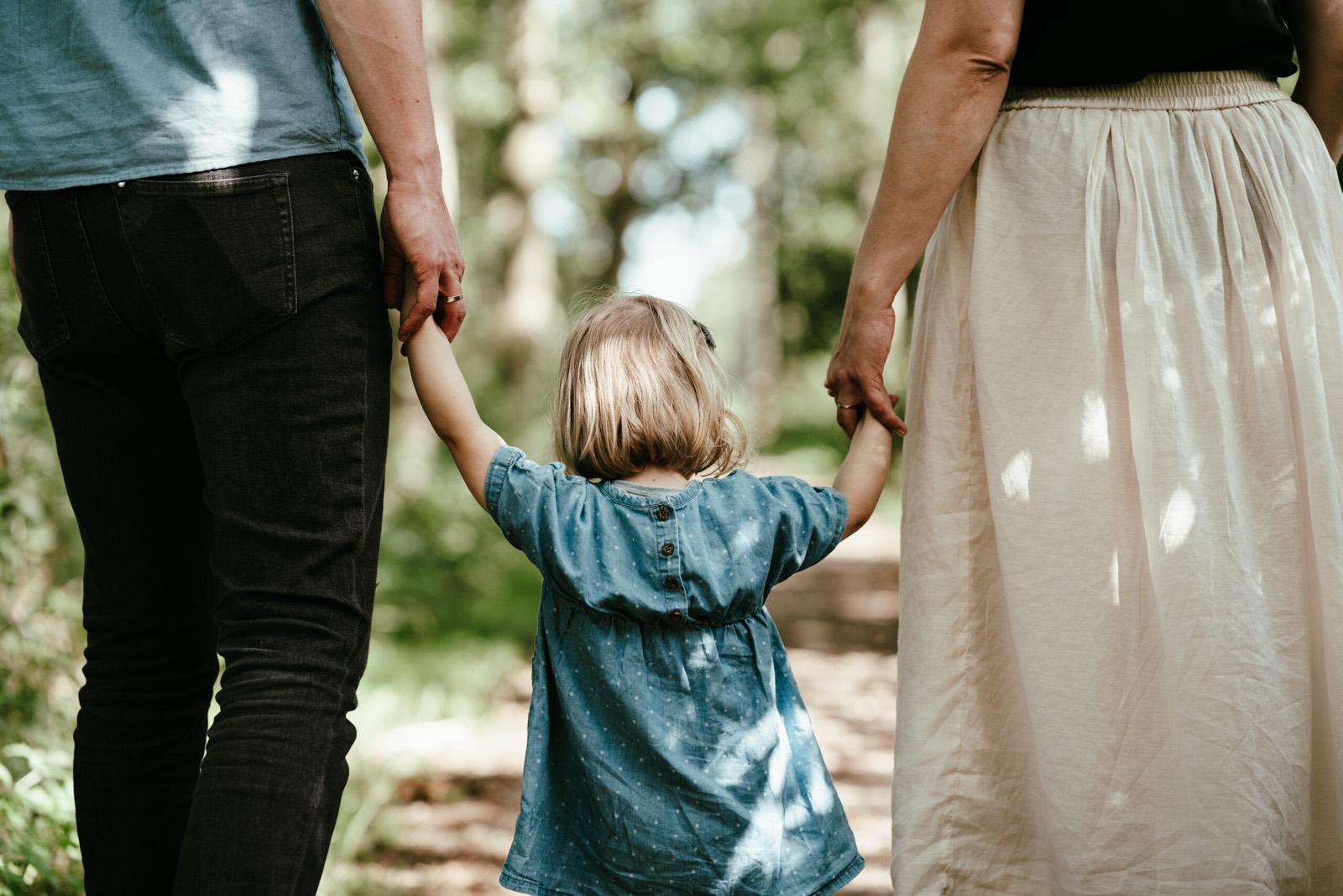 Peuter loopt hand in hand tussen haar ouders