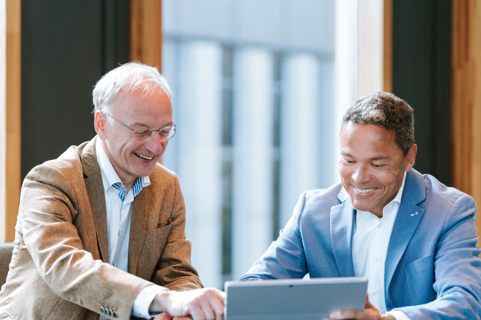 Twee collega’s van Farminform lachen samen bij een tablet