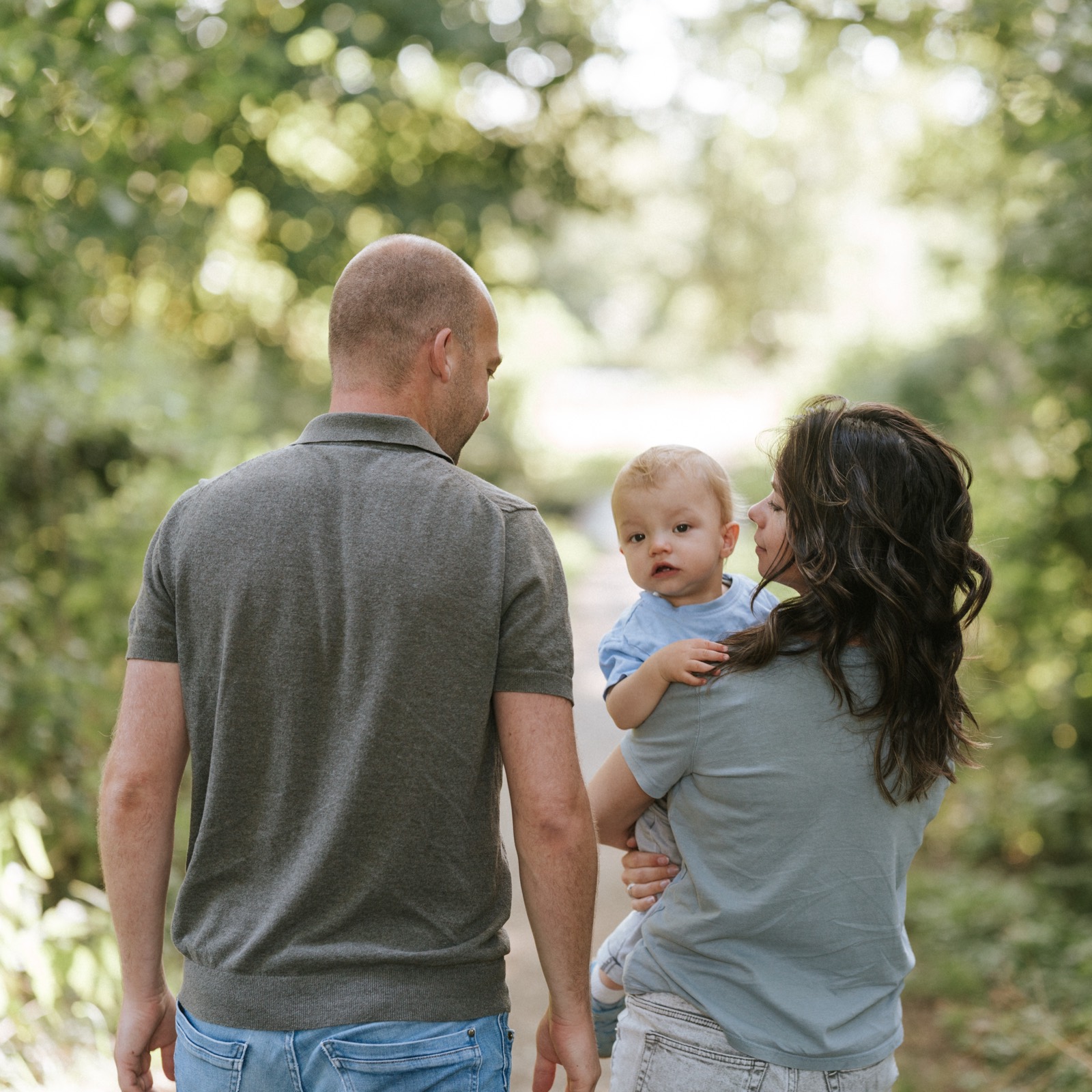 Ouders van achteren, het zoontje kijkt over de schouder van zijn moeder