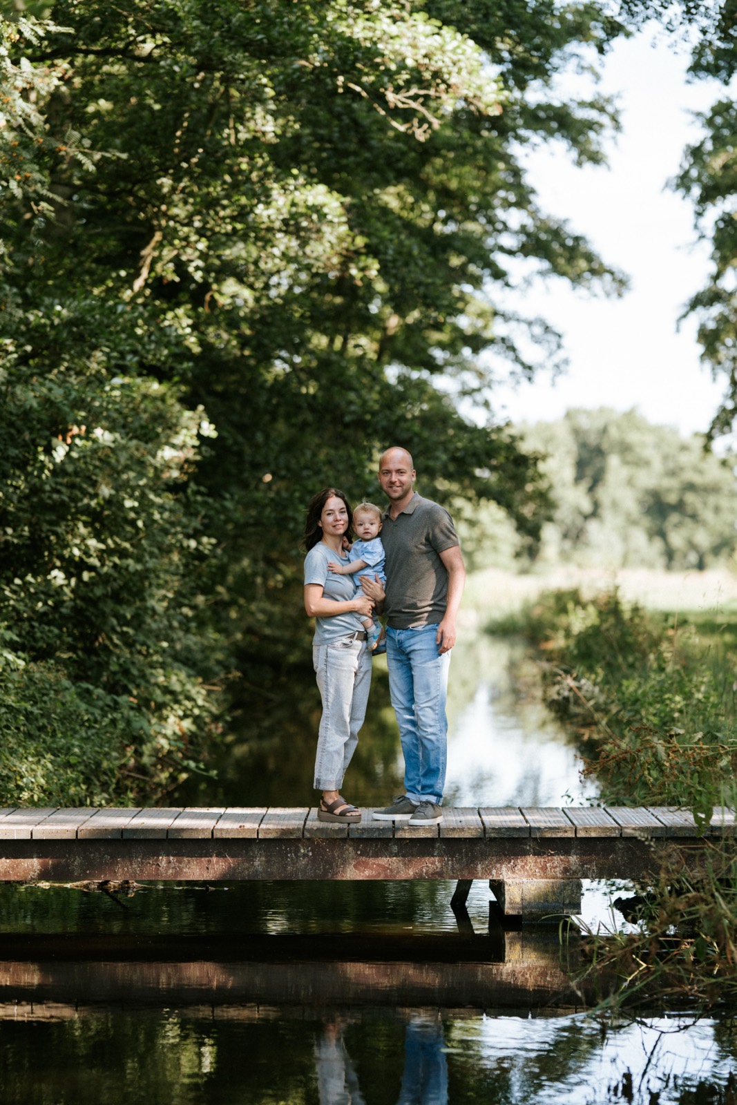 Ouders met hun zoontje op een houten bruggetje in de Goudse Hout
