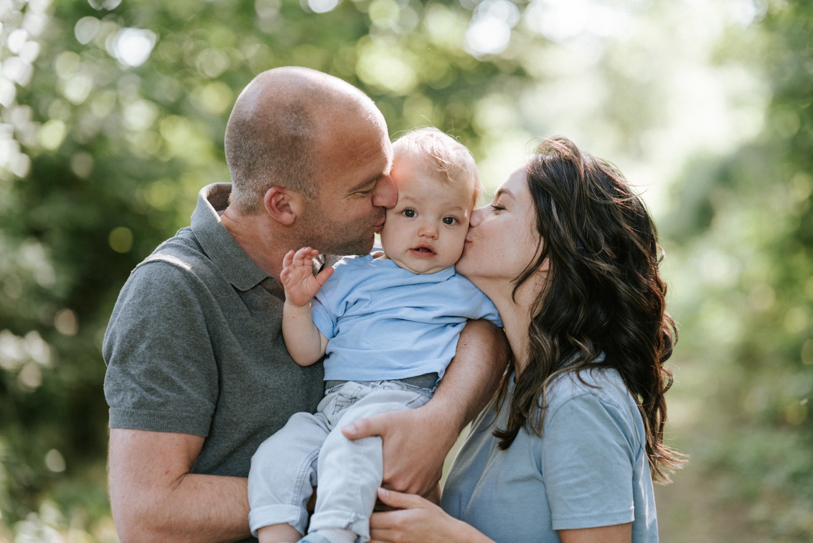 Ouders geven hun zoontje tegelijk een kus op de wangen