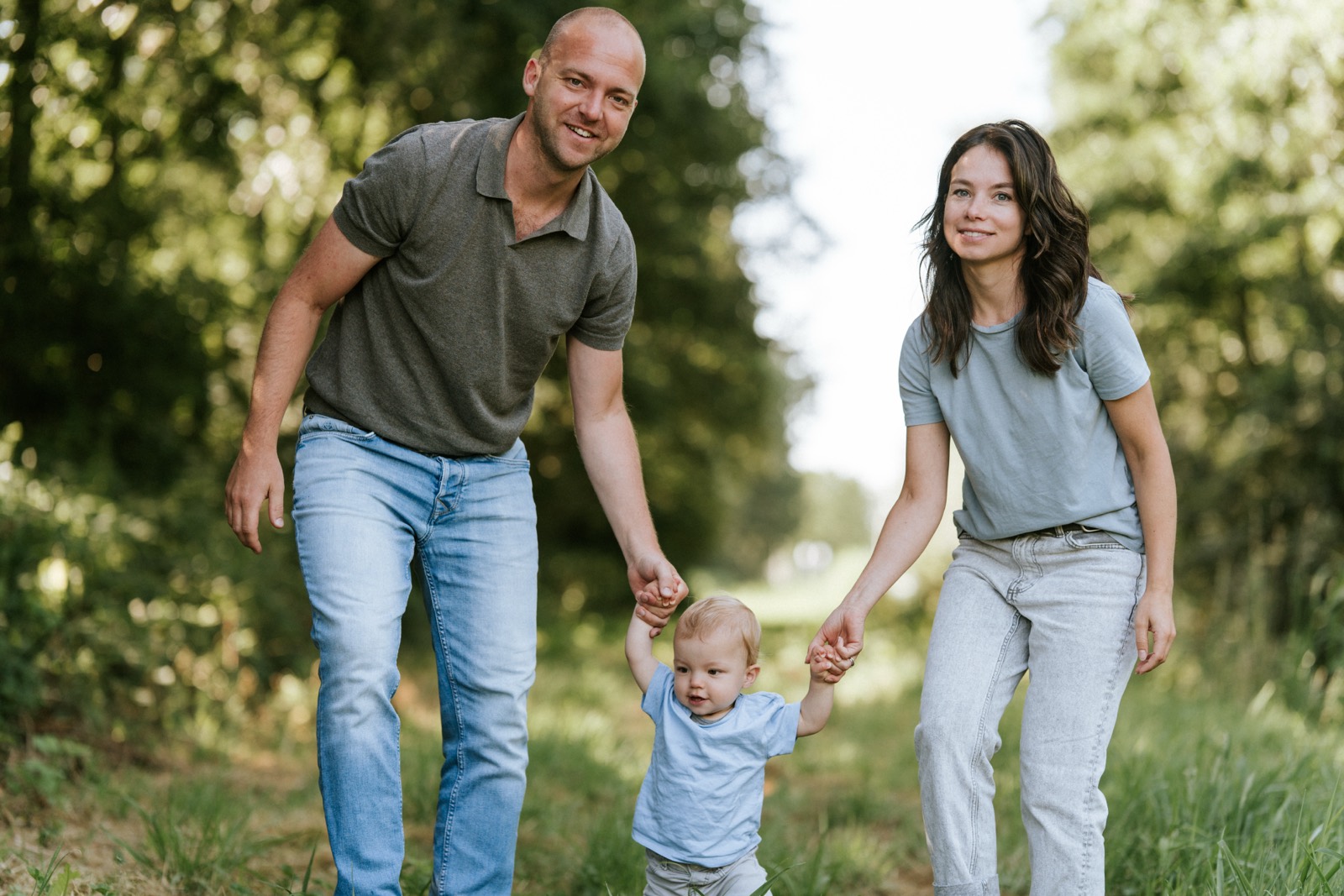 Ouders lopen met hun zoontje aan de hand over het bospad