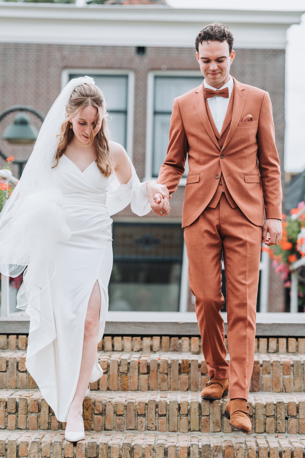 Bruid en bruidegom lopen hand in hand een stoep af