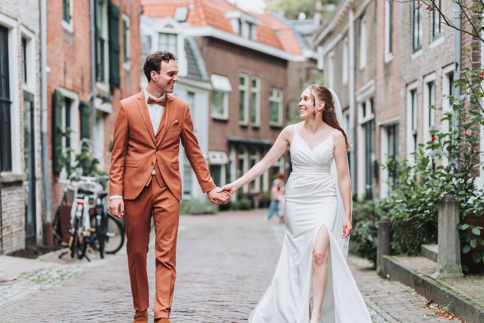 Bruidspaar hand in hand in een straat met oude gevels