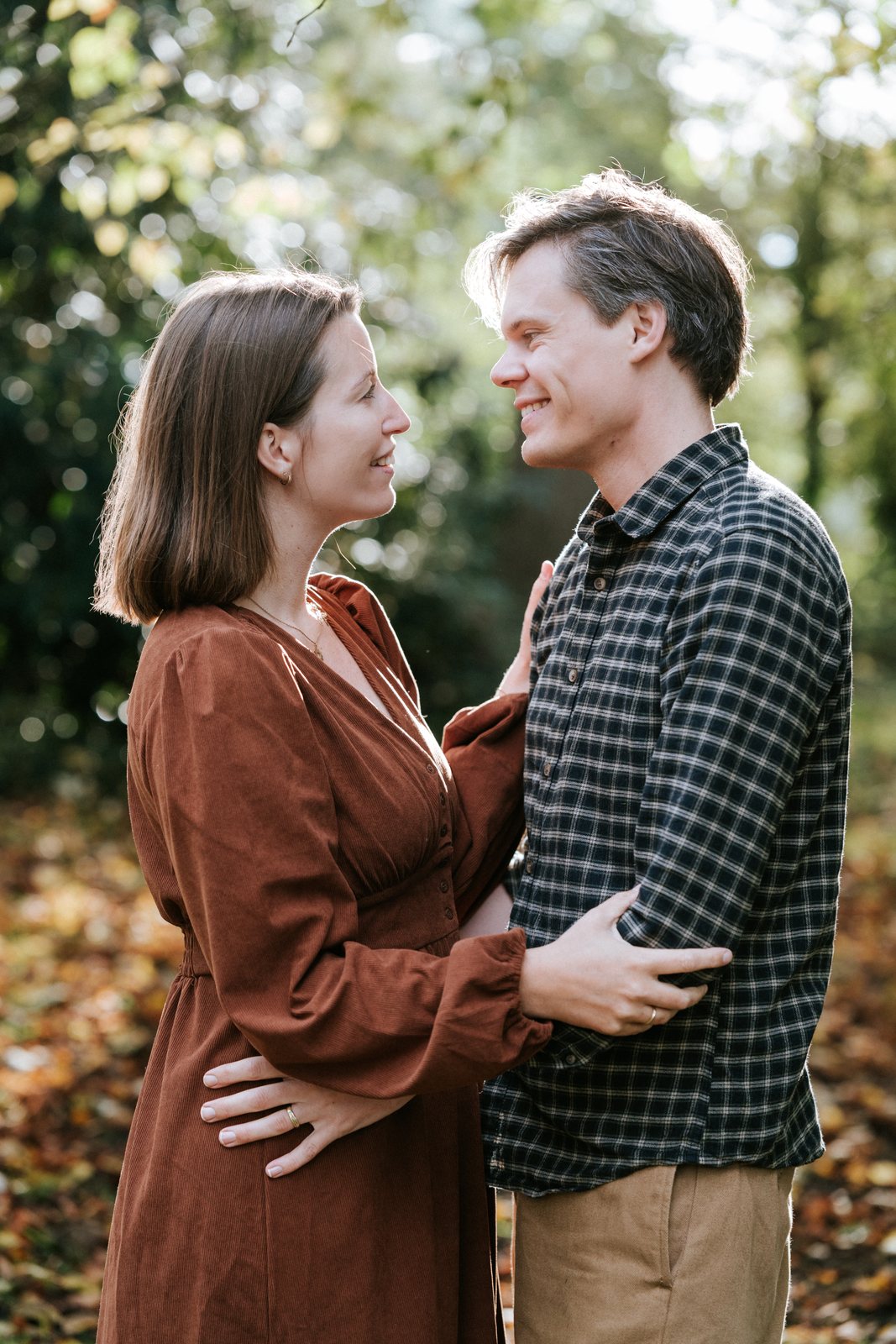 Ouders kijken elkaar lachend aan in het herfstlicht