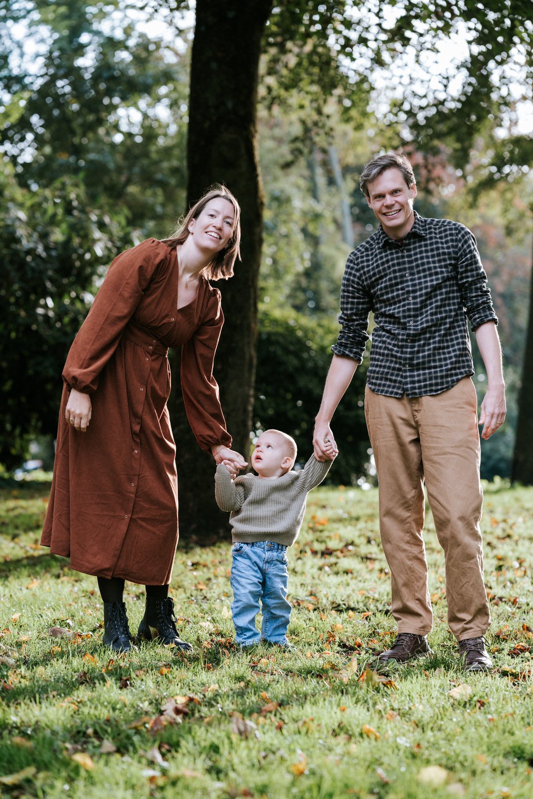 Ouders lopen met hun zoontje aan de hand over het gras in het park