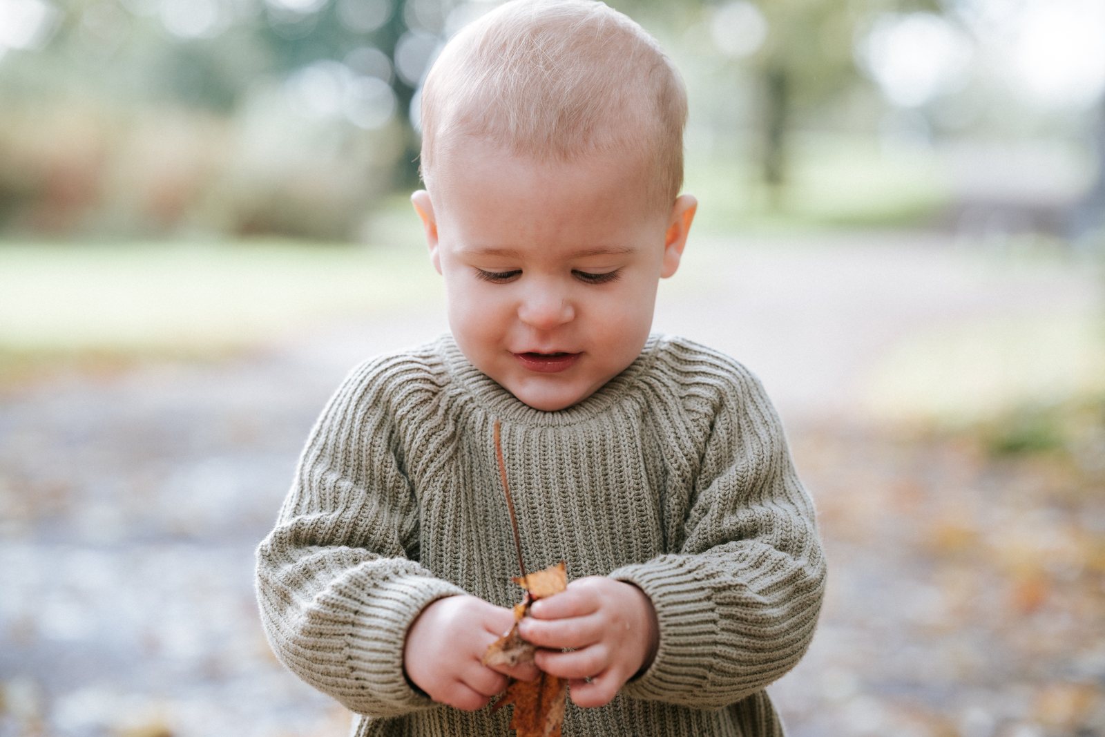 Peuter bekijkt een herfstblad in zijn handjes