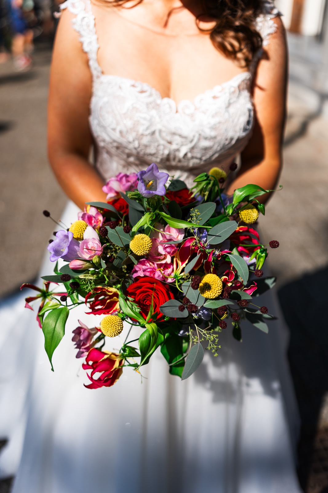 Kleurrijk bruidsboeket met rode en gele bloemen voor de trouwjurk