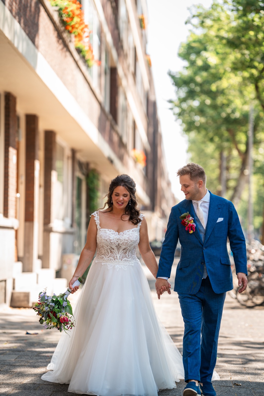 Bruidspaar loopt hand in hand over de stoep