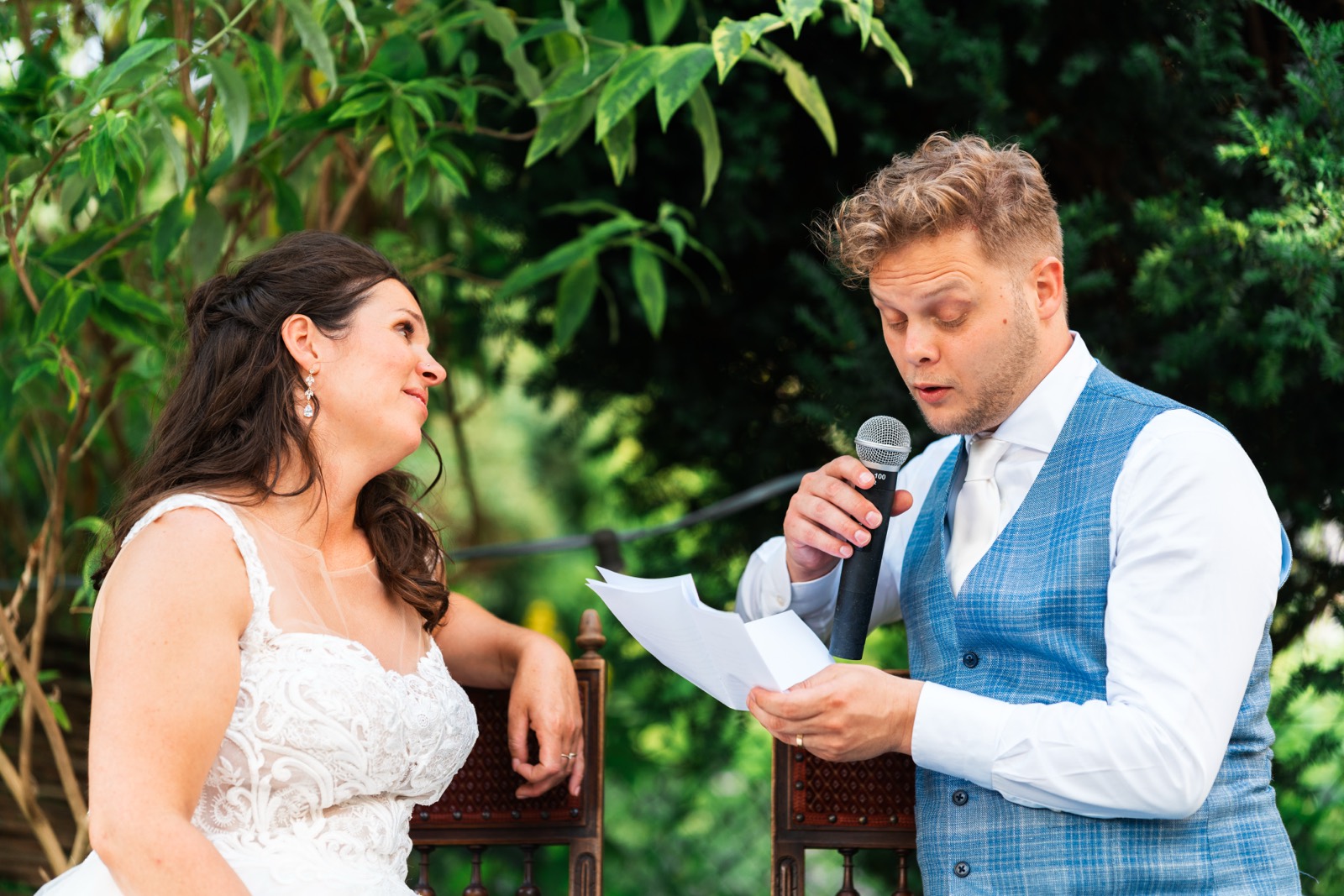 Bruidegom houdt met een microfoon een speech voor de bruid