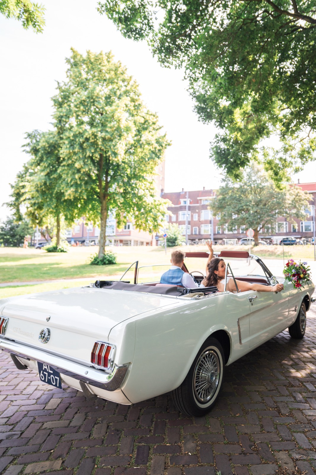 Witte Mustang cabriolet met het bruidspaar achterin
