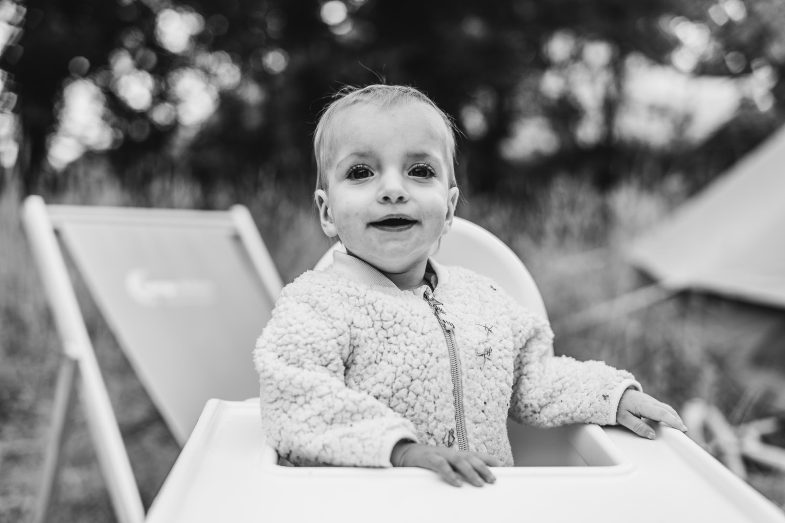 Lachend meisje in een teddyjasje in haar kinderstoel