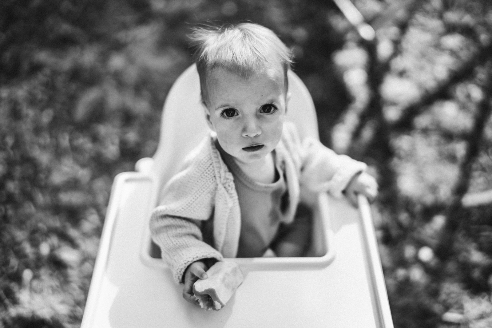Meisje in een kinderstoel kijkt van onderen op naar de camera