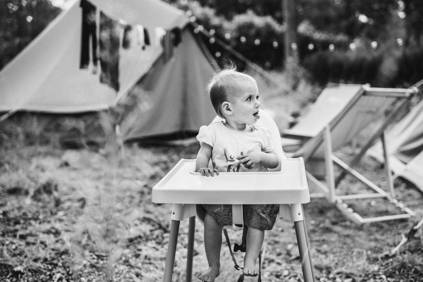 Meisje in een kinderstoel steekt haar tong uit en kijkt opzij