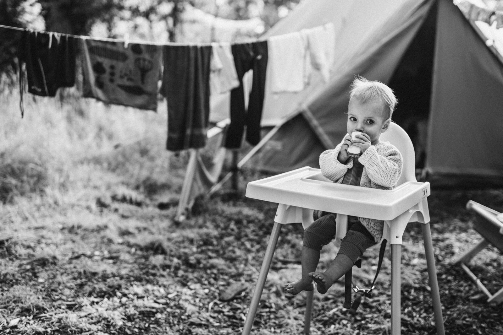 Meisje in een kinderstoel voor een waslijn en een tent