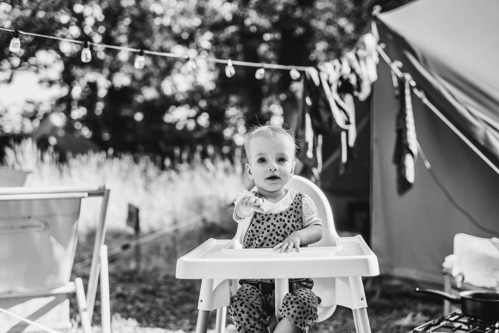 Meisje in een kinderstoel wijst naar de camera onder een lichtsnoer