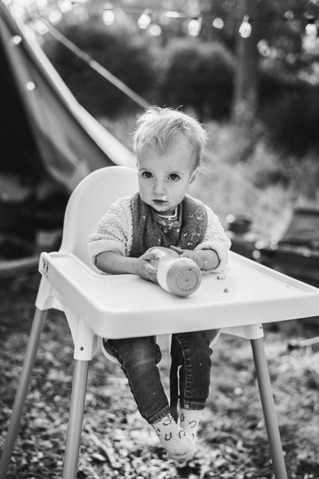 Zwart-witportret van een meisje van één in een kinderstoel voor een glijbaan