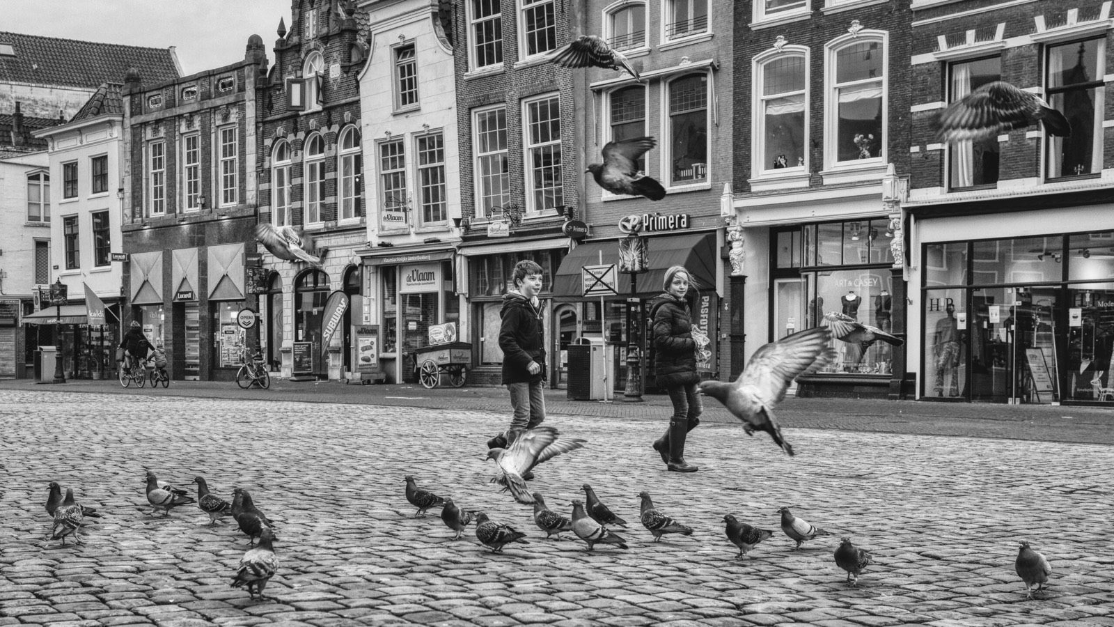 Zwart-witfoto van een marktplein met opvliegende duiven